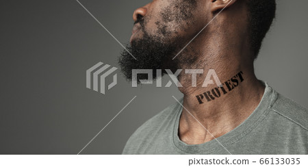 Close up portrait of a black man tired of racial discrimination has tattooed slogan on his neck Close up portrait of a black man tired of racial discrimination has tattooed slogan on his neck 66133035