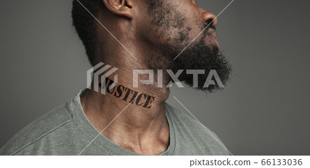 Close up portrait of a black man tired of racial discrimination has tattooed slogan on his neck Close up portrait of a black man tired of racial discrimination has tattooed slogan on his neck 66133036