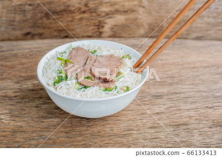 A bowl of Traditional Vietnamese beef soup Pho Bo at the dark old wooden background A bowl of Traditional Vietnamese beef soup Pho Bo at the dark old wooden background 66133413