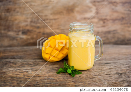 Mango smoothie in a glass Mason jar and mango on the old wooden background. Mango shake. 66134078