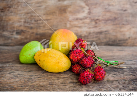 Tropical fruit on the old wooden background. Rambutan, banana, mango, guava. Tropical fruit on the old wooden background. Rambutan, banana, mango, guava. 66134144