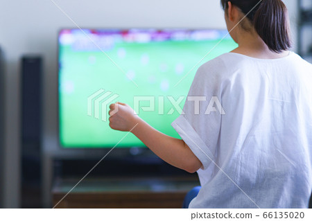 Image of a young woman watching sports at home on TV [Professional soccer video distribution service] 66135020