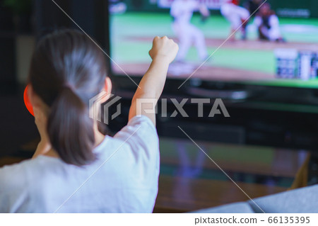 Image of a young woman watching sports at home on TV [Professional baseball video distribution service] 66135395