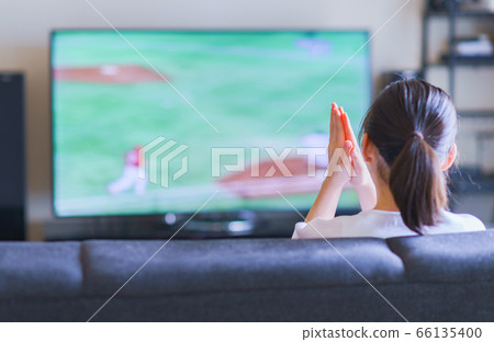 Image of a young woman watching sports at home on TV [Professional baseball video distribution service] 66135400