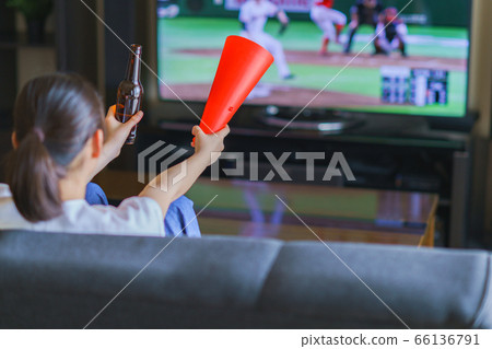 Image of a young woman watching sports at home on TV [Professional baseball video distribution service] 66136791