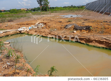 MALACCA, MALAYSIA -OCTOBER 26, 2015: Check dam or silt trap at the construction site. Soil and mud from the construction site in strained and precipitated. Only clean water discharged. MALACCA, MALAYSIA -OCTOBER 26, 2015: Check dam or silt trap at the construction site. Soil and mud from the construction site in strained and precipitated. Only clean water discharged. 66136805