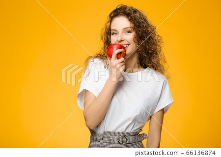 Pretty curly girl with red apple in studio Pretty curly girl with red apple in studio 66136874