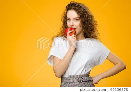 Pretty curly girl with red apple in studio Pretty curly girl with red apple in studio 66136878