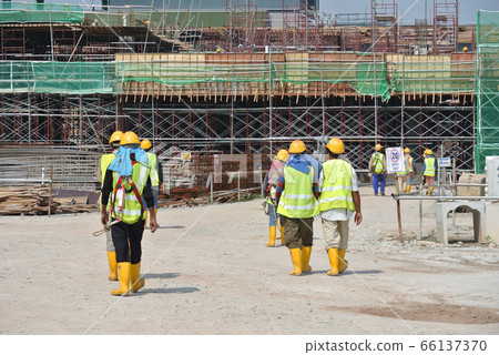 JOHOR, MALAYSIA -JUNE 17, 2016: Construction workers walking in the construction site. Wearing proper PPE for their safety. JOHOR, MALAYSIA -JUNE 17, 2016: Construction workers walking in the construction site. Wearing proper PPE for their safety. 66137370