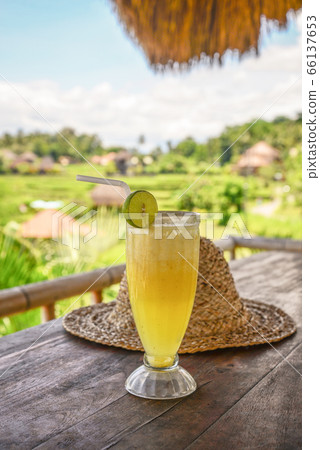 Pineapple juice and straw hat on wooden table 66137653