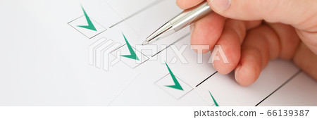 Male businessman hand hold silver pen and make green check mark closeup Male businessman hand hold silver pen and make green check mark closeup 66139387