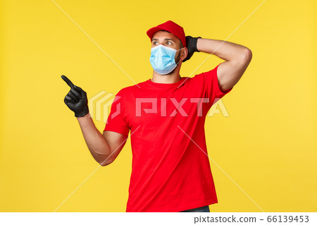 Express delivery during pandemic, covid-19, safe shipping, online shopping concept. Shocked and impressed courier in red uniform, medical mask and gloves, point and staring upper left corner Express delivery during pandemic, covid-19, safe shipping, online shopping concept. Shocked and impressed courier in red uniform, medical mask and gloves, point and staring upper left corner 66139453
