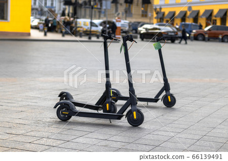 Black electric scooters parked outside for self 66139491