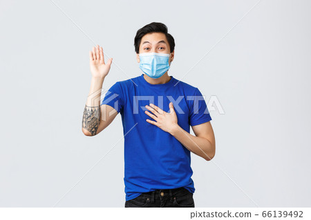 Different emotions, social distancing, self-quarantine on covid-19 and lifestyle concept. Sincere and honest asian guy in medical mask telling truth, making promise with hand raised and one on heart Different emotions, social distancing, self-quarantine on covid-19 and lifestyle concept. Sincere and honest asian guy in medical mask telling truth, making promise with hand raised and one on heart 66139492