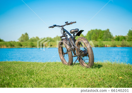 Electric bike with thick wheels near the lake. Electric bike with thick wheels near the lake. 66140201