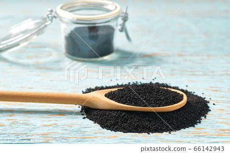 black cumin in a wooden spoon and open glass jar 66142943