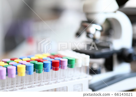 Test tube with colored caps next to microscope 66143021