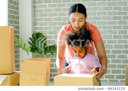 Mother and American African girl help together to set or pack paper box or carton move new house Mother and American African girl help together to set or pack paper box or carton move new house 66143128
