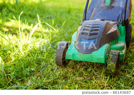 Lawn mower cutting green grass in backyard Lawn mower cutting green grass in backyard 66143697
