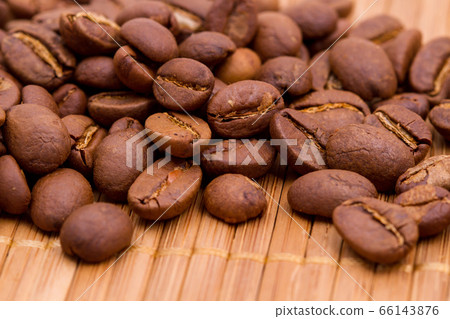 Scattering of roasted coffee beans on top of a wooden cutting board Scattering of roasted coffee beans on top of a wooden cutting board 66143876