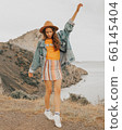Beautiful girl in a hat on a summer vacation in the mountains on nature. Blue sky and sea. 66145404