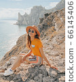 Beautiful girl in a hat on a summer vacation in the mountains on nature. Blue sky and sea. 66145406