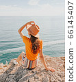Beautiful girl in a hat on a summer vacation in the mountains on nature. Blue sky and sea. 66145407
