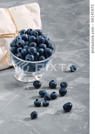 Blueberries on a black background,, fresh berry in a bowl on a concrete background with a wrapped envelope with a berry. copies of space, delivery of berries. 66145973