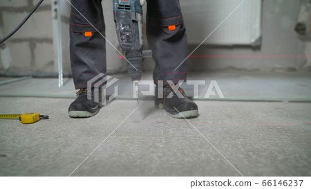 Worker drills a concrete floor. Drill, concrete floor, worker Worker drills a concrete floor. Drill, concrete floor, worker 66146237