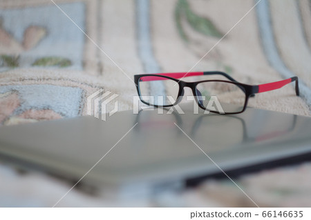 Picture of eyeglasses and laptop on bed in Picture of eyeglasses and laptop on bed in 66146635