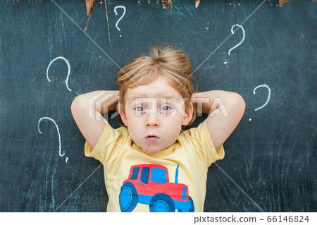 Top view of a little blond kid boy with question mark on blackboard. Concept for confusion, brainstorming and choice Top view of a little blond kid boy with question mark on blackboard. Concept for confusion, brainstorming and choice 66146824