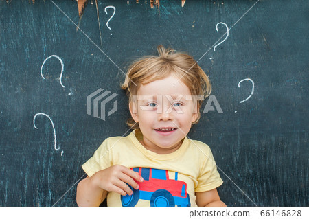 Top view of a little blond kid boy with question mark on blackboard. Concept for confusion, brainstorming and choice Top view of a little blond kid boy with question mark on blackboard. Concept for confusion, brainstorming and choice 66146828