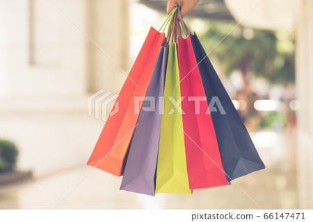 Close up photo of human hand holding colorful shopping bags 66147471