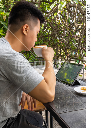 Vertical photo of businessman using tablet and drinking cappuccino Vertical photo of businessman using tablet and drinking cappuccino 66147485
