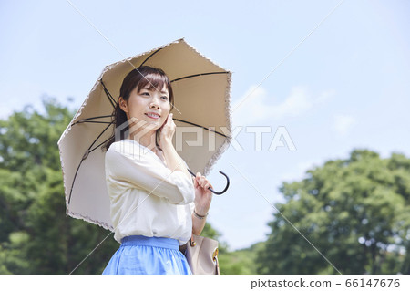 A woman holding a parasol under the blue sky A woman holding a parasol under the blue sky 66147676
