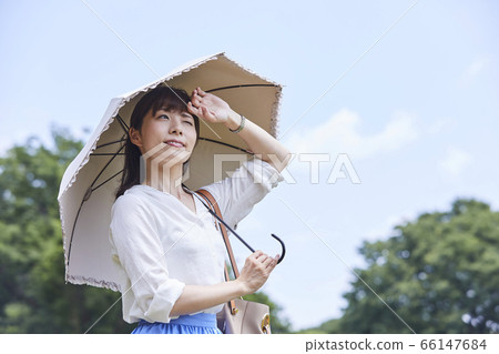 A woman holding a parasol under the blue sky 66147684