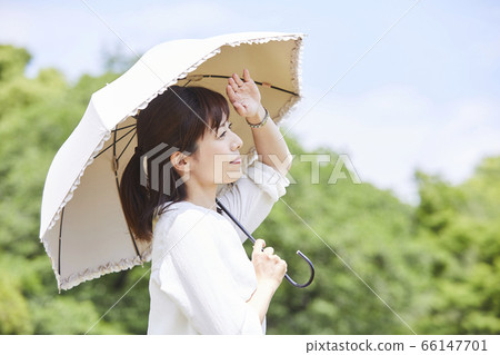 A woman holding a parasol under the blue sky A woman holding a parasol under the blue sky 66147701