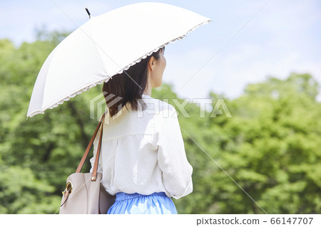 一個女人在藍色的天空下舉行陽傘 一個女人在藍色的天空下舉行陽傘 66147707
