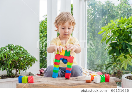 Cute little kid boy with playing with lots of colorful plastic blocks indoor. Active child having fun with building and creating of tower. Promotion of skills and creativity 66151626