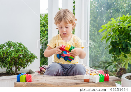 Cute little kid boy with playing with lots of colorful plastic blocks indoor. Active child having fun with building and creating of tower. Promotion of skills and creativity Cute little kid boy with playing with lots of colorful plastic blocks indoor. Active child having fun with building and creating of tower. Promotion of skills and creativity 66151634
