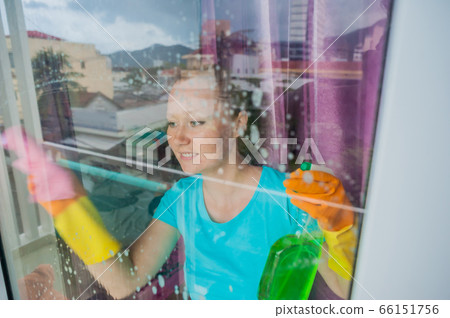 Beautiful female maid doing the housework while using a spray, washing windows 66151756