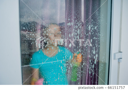 Beautiful female maid doing the housework while using a spray, washing windows 66151757