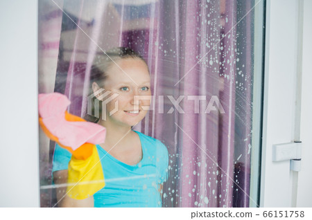 Beautiful female maid doing the housework while using a spray, washing windows 66151758