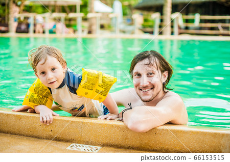 Young cheerful father and son in a swimming pool Young cheerful father and son in a swimming pool 66153515