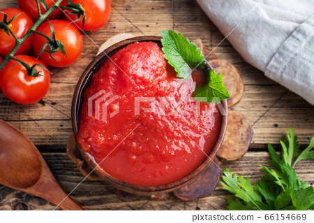 Tomatoes in their own juice or Tomato paste in a wooden bowl and fresh tomatoes on a rustic wooden table. 66154669