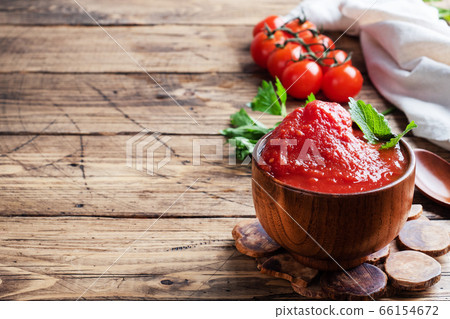Tomatoes in their own juice or Tomato paste in a wooden bowl and fresh tomatoes on a rustic wooden table. Copy space 66154672