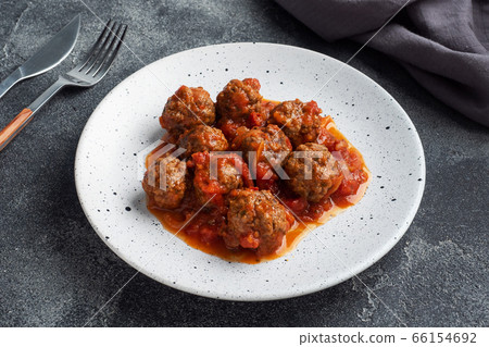 Beef meatballs stewed in tomato sauce on a plate. Dark concrete background. 66154692