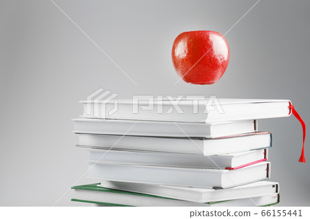 A red Apple hangs above the books on a white 66155441