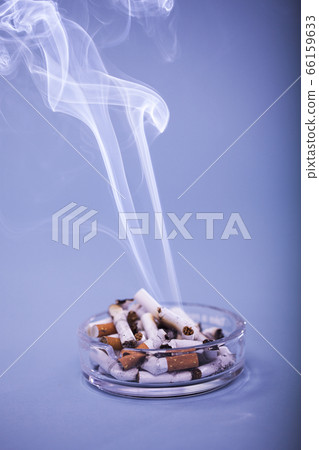 Cigarette smoke rising from the overflowing butts 66159633