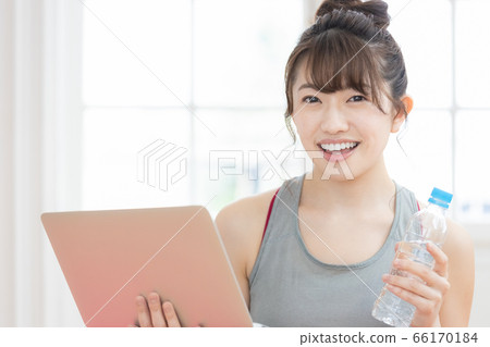 Woman looking at a laptop wearing training wear Woman looking at a laptop wearing training wear 66170184